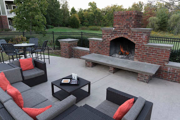 Outdoor patio with brick fireplace and wicker furniture at Wyndchase Aspen Grove Apartments, Tennessee, 37067