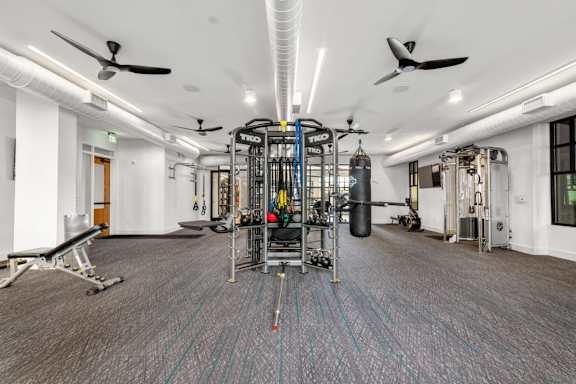A gym with a variety of equipment including a punching bag and a weight rack.