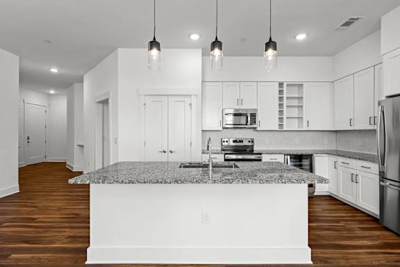 A modern kitchen with a granite countertop and stainless steel appliances.