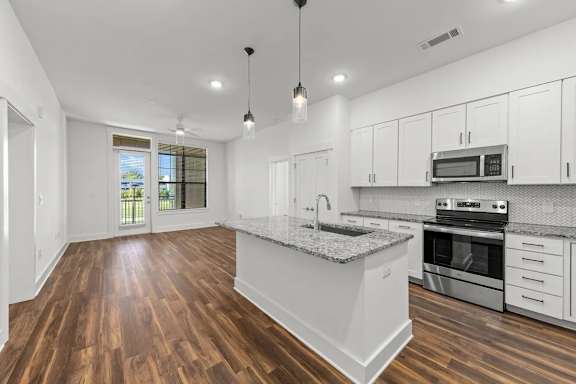 A kitchen with white cabinets and a granite countertop.