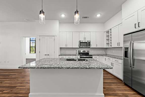 A modern kitchen with a granite countertop and stainless steel appliances.