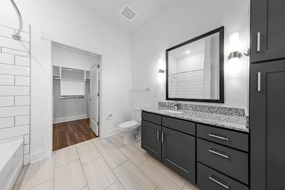 A bathroom with a toilet, sink, and a mirror.