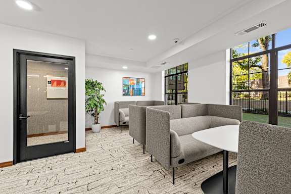 A modern waiting room with grey couches and a black table.