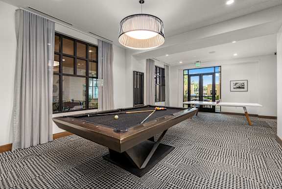 A pool table is in the middle of a room with a carpeted floor.