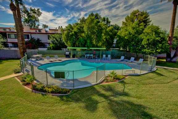 A round above ground pool surrounded by a fence and trees.