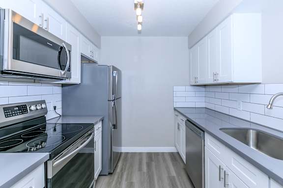 A kitchen with a stove, refrigerator, and microwave.