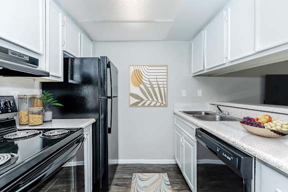 A kitchen with black appliances and white cabinets.