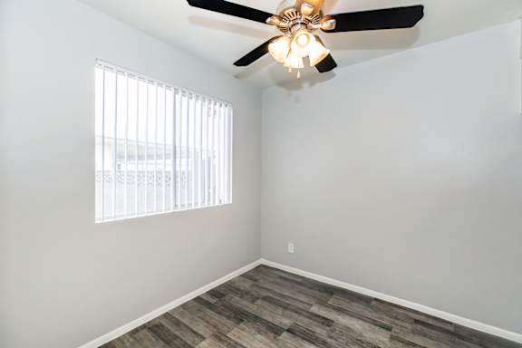 A room with a ceiling fan and a window with blinds.