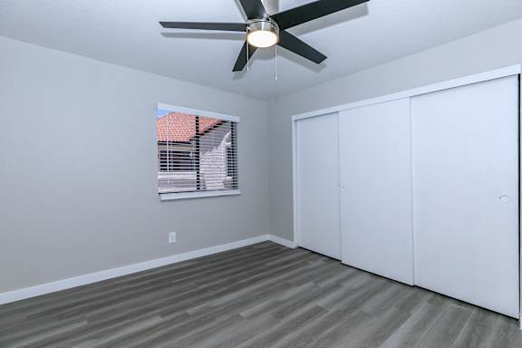 A room with a ceiling fan and a window with blinds.