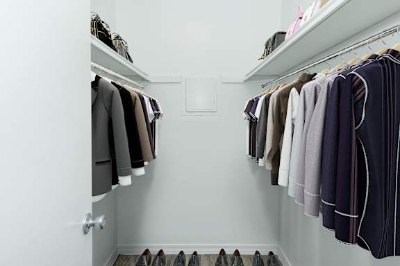 A white closet with clothes and shoes.