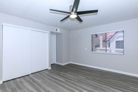 A room with a ceiling fan and a window with blinds.