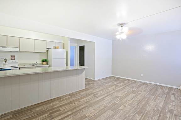A kitchen with a refrigerator, sink, and cabinets.
