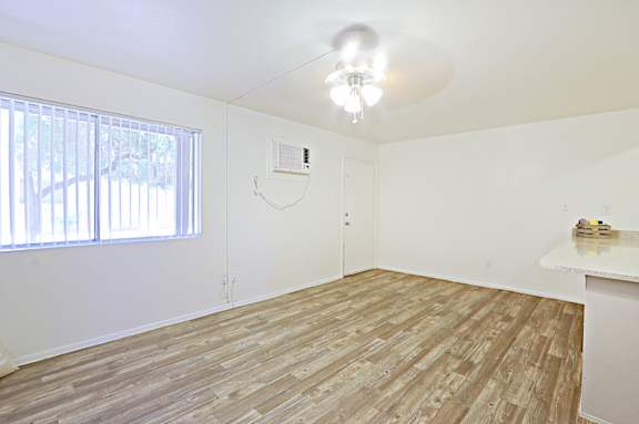 A room with a ceiling fan and a window with blinds.