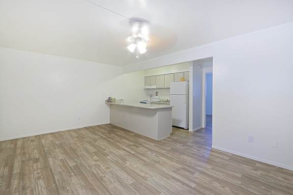 A kitchen area with a white counter and a fridge.