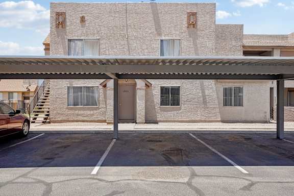 A parking lot in front of a building with a car parked.