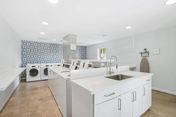 A kitchen with a white counter top and a sink. at The Viridian Apartments, Arizona