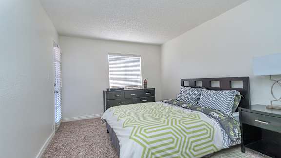 A bedroom with a bed, dresser, and window.