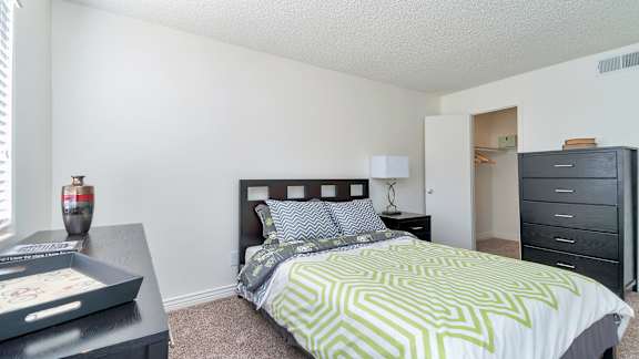 A bedroom with a bed, nightstand, and a dresser.