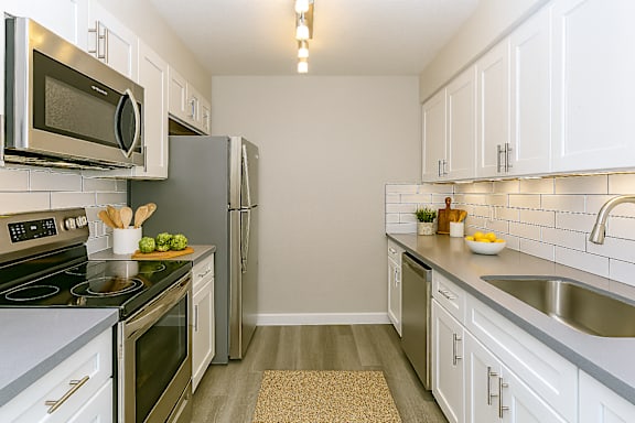 A kitchen with white cabinets and a black counter top.