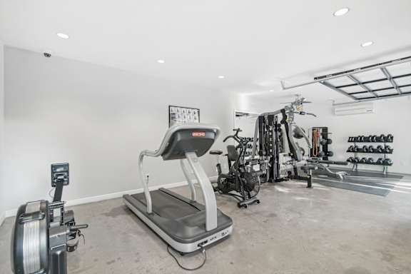 A gym with a treadmill, weights and exercise equipment.