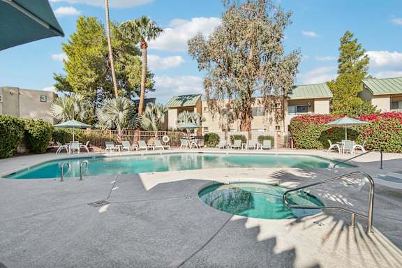 A large outdoor swimming pool surrounded by trees and lounge chairs.