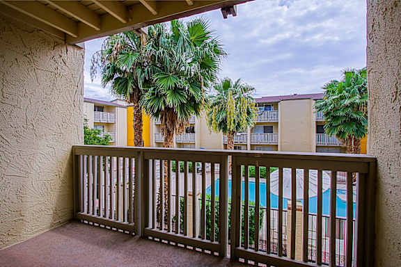 A balcony with a pool and palm trees in the background.
