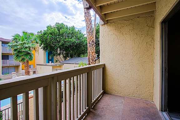 A balcony with a view of a pool and buildings.