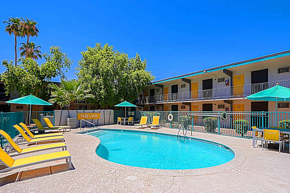 A pool surrounded by yellow sun loungers and blue umbrellas.