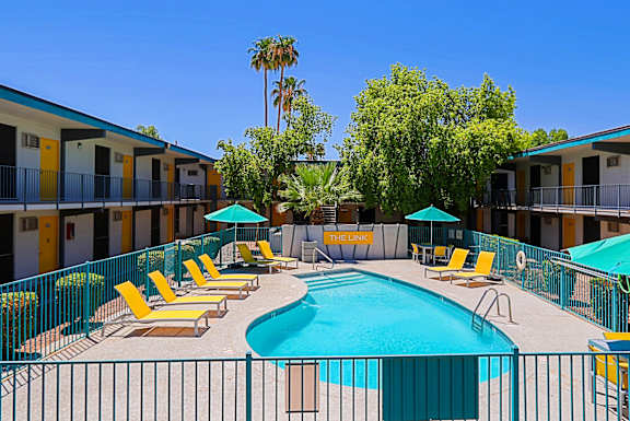 A pool surrounded by yellow chairs and umbrellas.