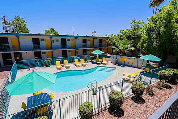 A pool area with a blue pool and yellow chairs.