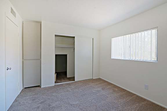 A room with a carpeted floor and a window with blinds.