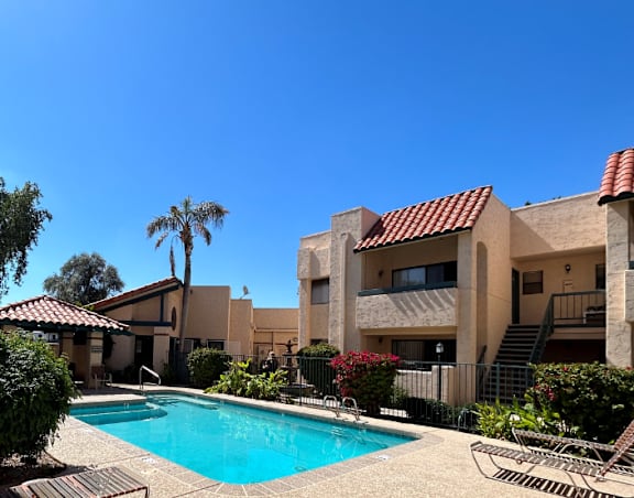 A pool surrounded by a patio and a building.