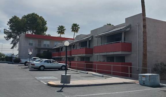 A parking lot with a building and a tree in the background.