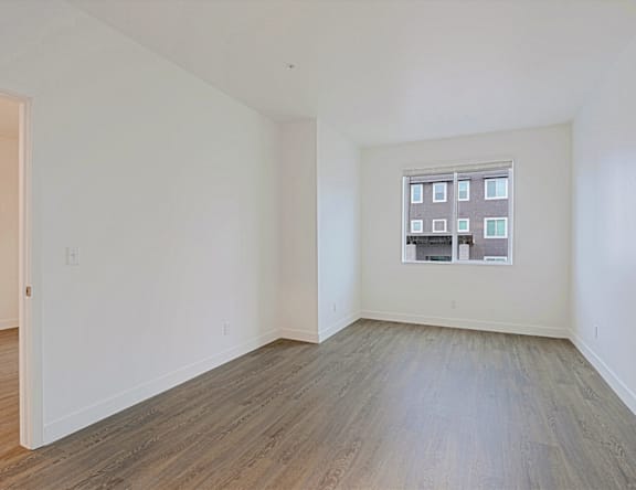 Empty room with a window and wooden flooring.