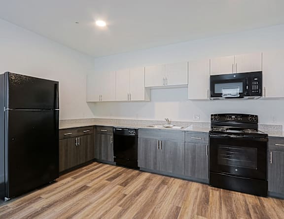 A kitchen with black appliances and wooden floors.