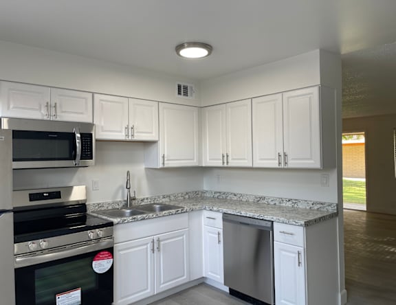 A kitchen with white cabinets and a granite countertop.