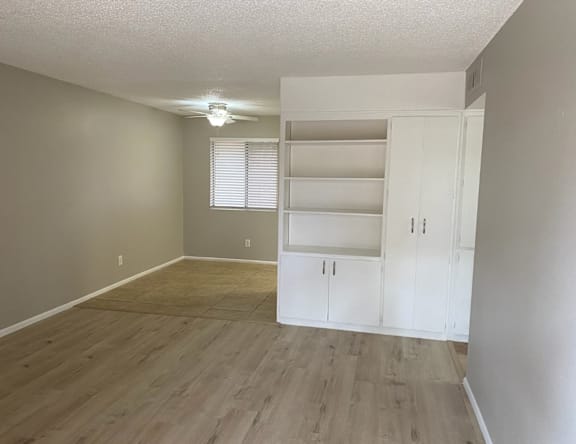 A room with a white cabinet and a window with blinds.