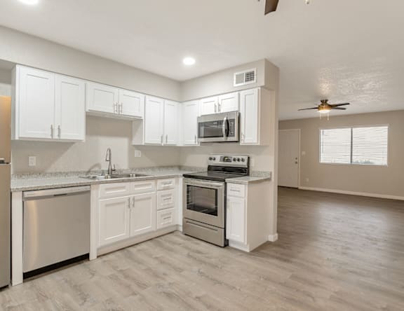 A modern kitchen with white cabinets and stainless steel appliances.