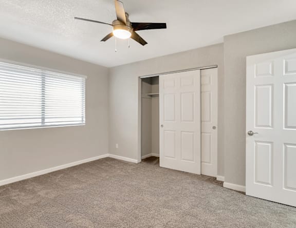A room with a ceiling fan and two doors.