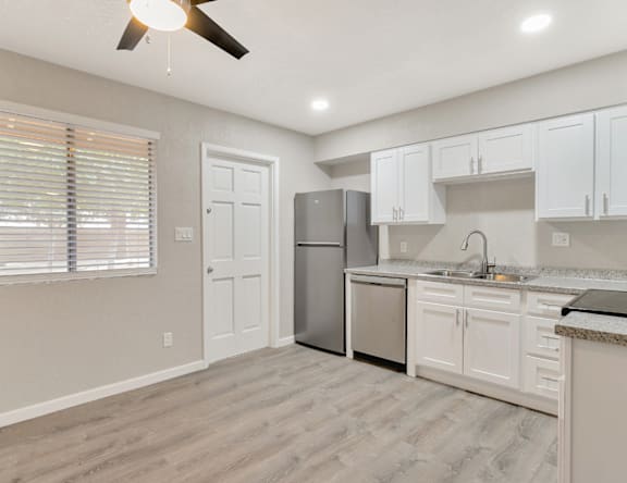 A kitchen with a refrigerator, sink, and cabinets.