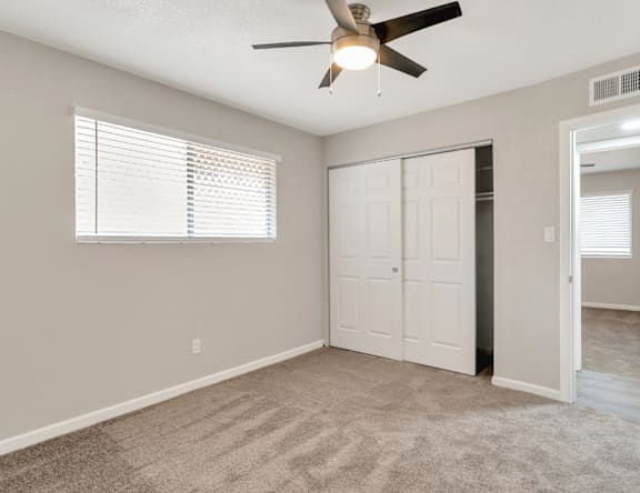 A room with a ceiling fan and a white door.