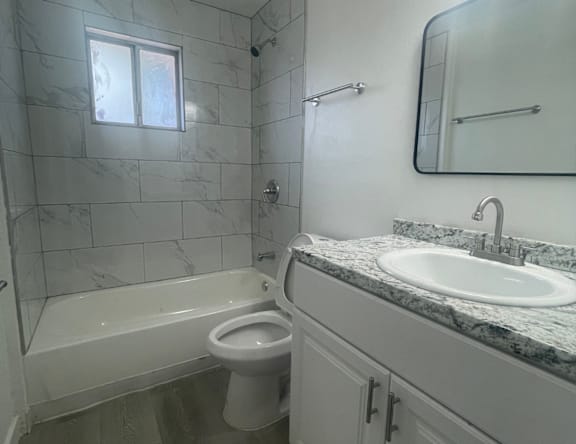 A white toilet in a bathroom with a marble countertop and a small window.