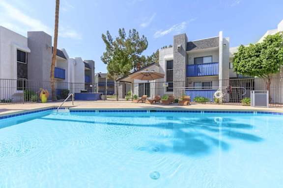 A swimming pool in front of a building with a blue sky in the background.