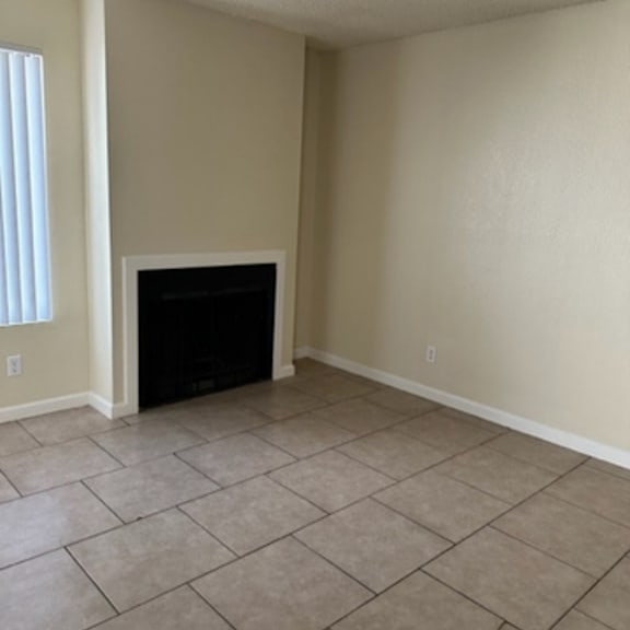 A living room with a fireplace and tiled floor.