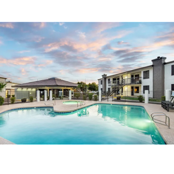 A swimming pool in front of a building with a balcony.