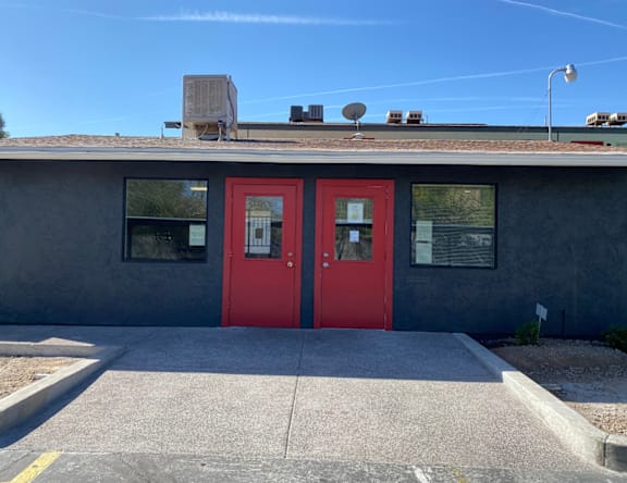 A building with a red door and satellite dish on the roof.