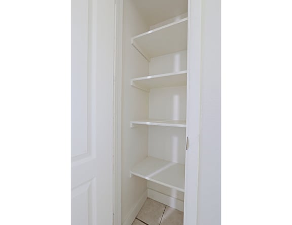 A white open pantry with shelves and a door.