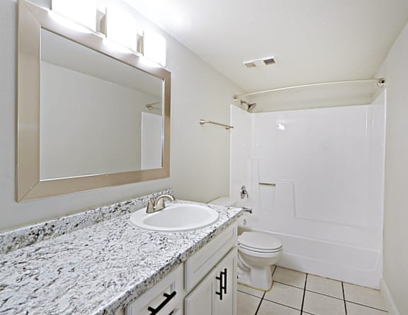 A bathroom with a sink, toilet and mirror.