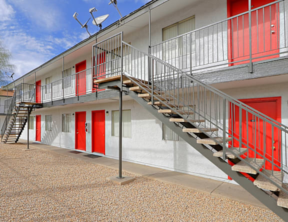 A building with red doors and stairs leading to the second floor.