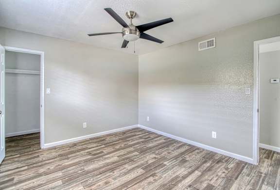 A room with a ceiling fan and wooden flooring.
